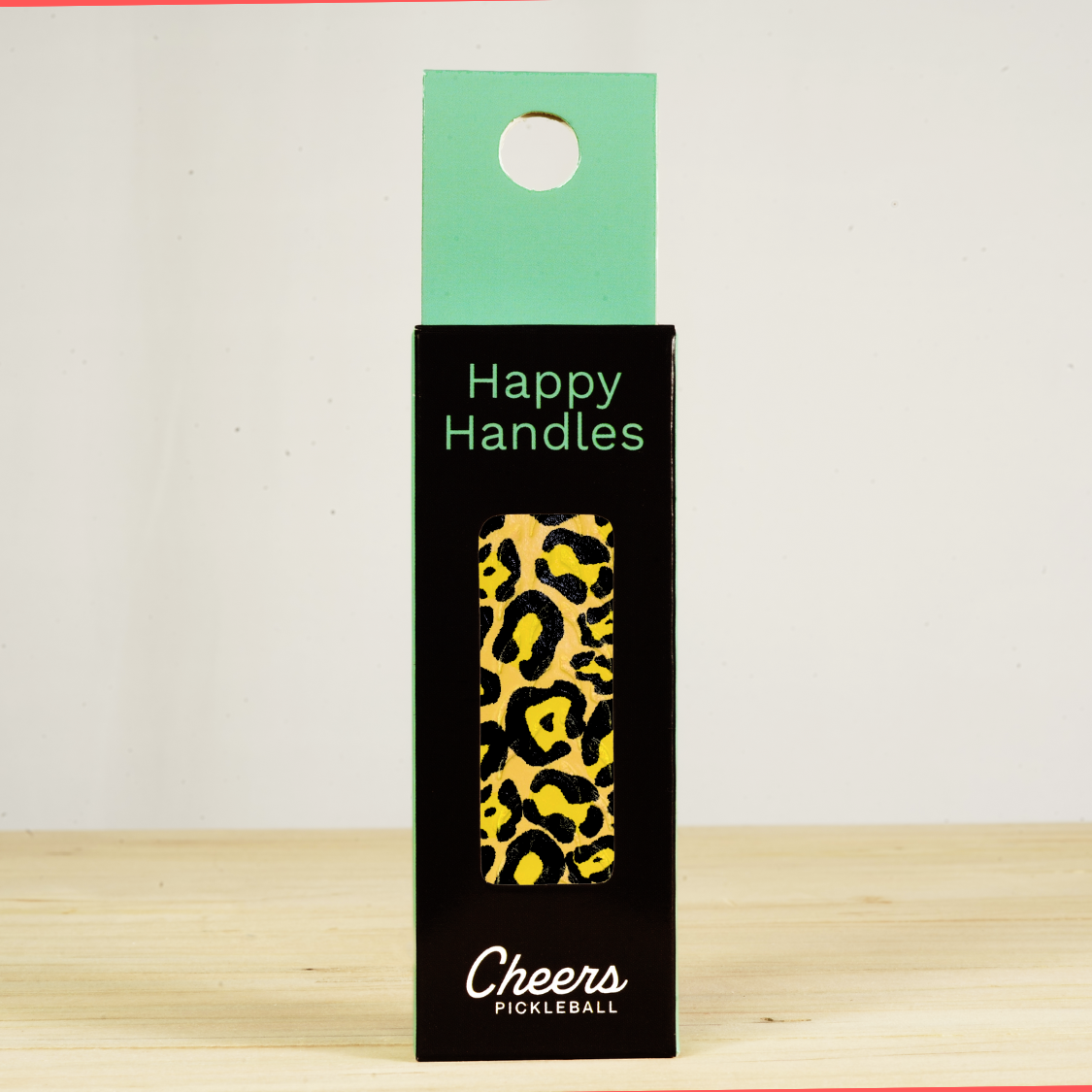 Happy Handles Leopard Pickleball Grip in its packaging, featuring a black and yellow leopard skin print, visible through the product box window