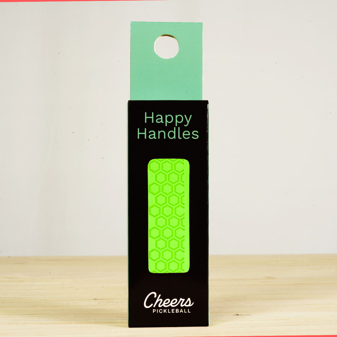 Happy Handles  Neon Green Pickleball Grip in its packaging, featuring hexagon textured print, visible through the product box window