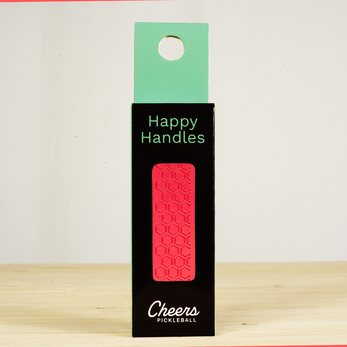 Happy Handles Radiant Red Pickleball Grip in its packaging, featuring hexagon textured print, visible through the product box window