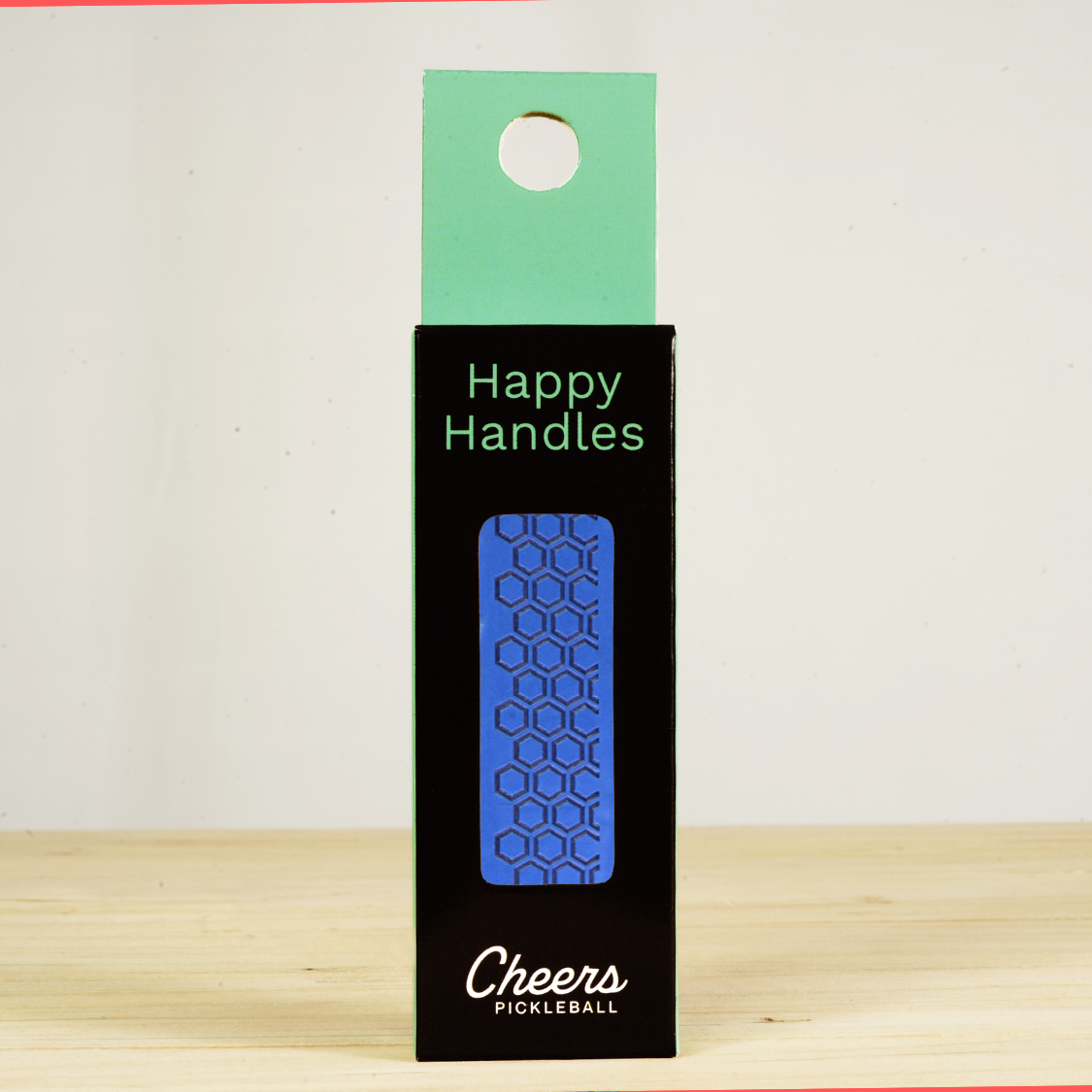 Happy Handles Pure Atlantic Blue Pickleball Grip in its packaging, featuring hexagon textured print, visible through the product box window