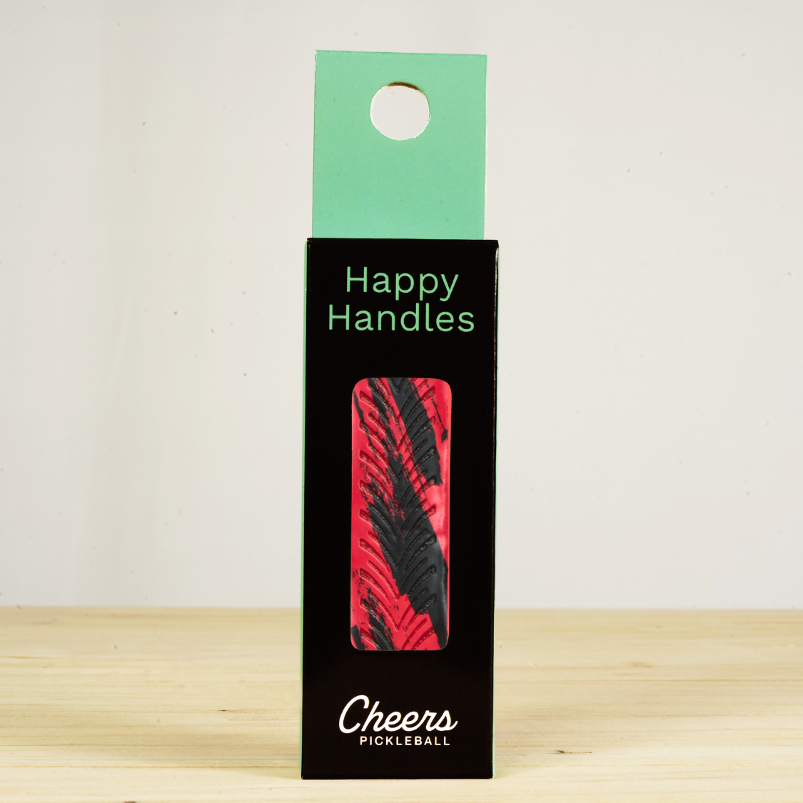 Happy Handles Brushed Red Pickleball Grip in its packaging, featuring black stripe marbling on red, visible through the product box window