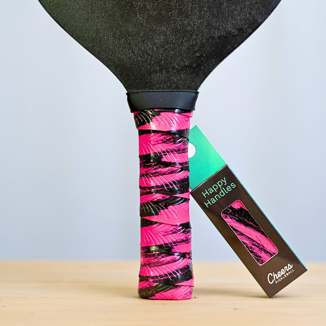 Happy Handles Brushed Pink Pickleball Grip in black brush mark through pink, displayed on a paddle