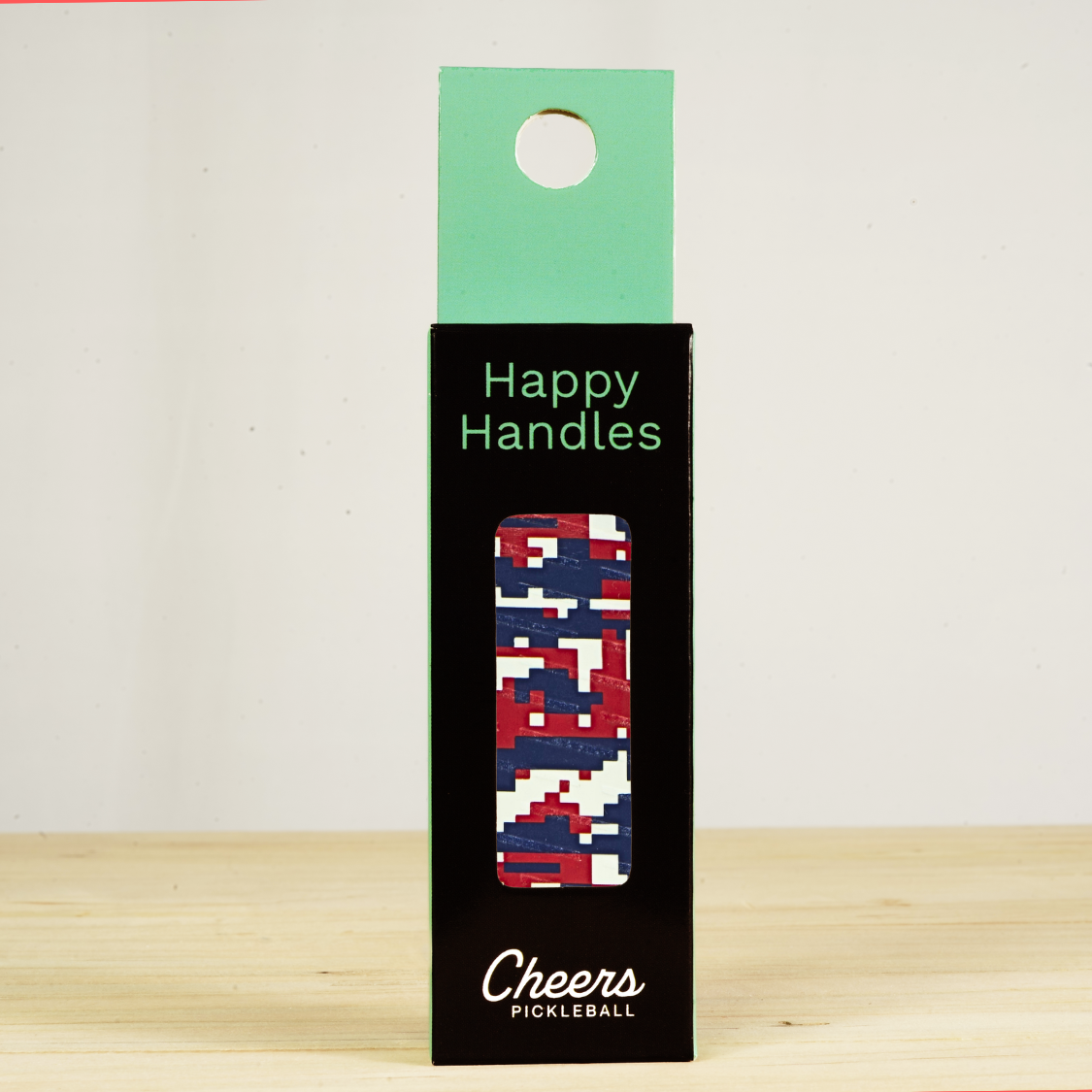 Happy Handles Digital Camo Pickleball Grip in its packaging, featuring red, blue, and white digital camo, visible through the product box window