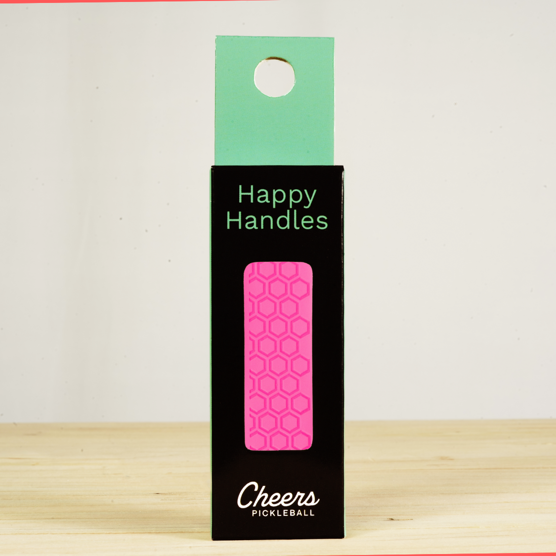 Happy Handles Pure Hot Pink Pickleball Grip in its packaging, featuring hexagon textured print, visible through the product box window