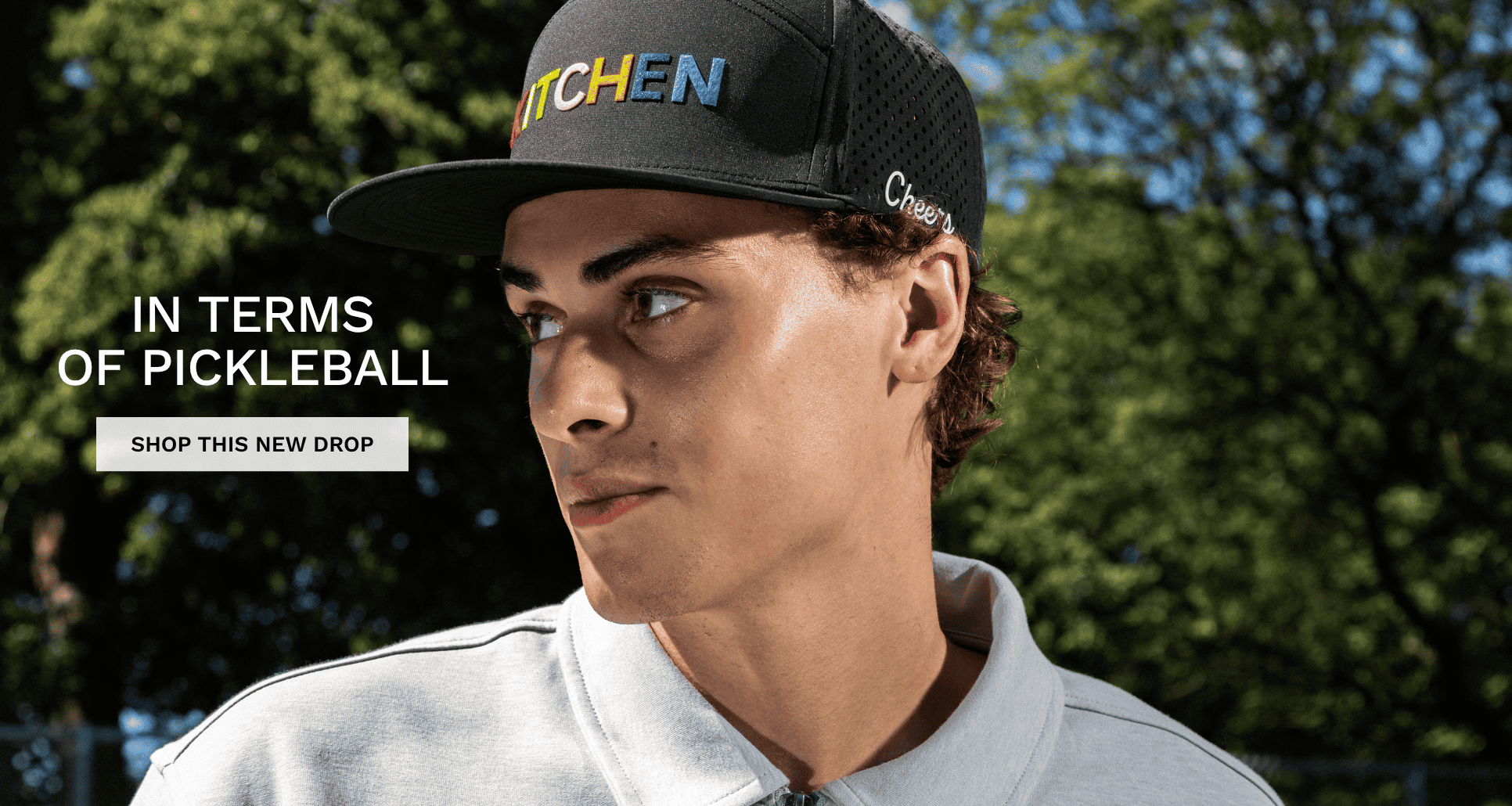 New Collection called "In terms of pickleball". Person wearing a black cap with text, standing outdoors with trees in the background