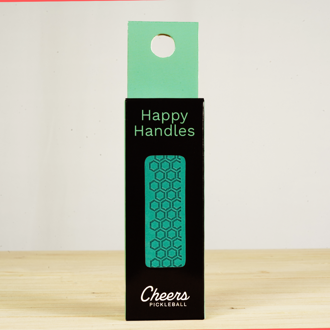 Happy Handles Pure Lagoon Pickleball Grip in its packaging, featuring hexagon textured print, visible through the product box window