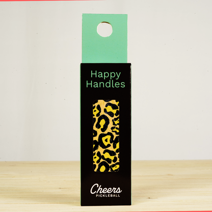 Happy Handles Leopard Pickleball Grip in its packaging, featuring a black and yellow leopard skin print, visible through the product box window
