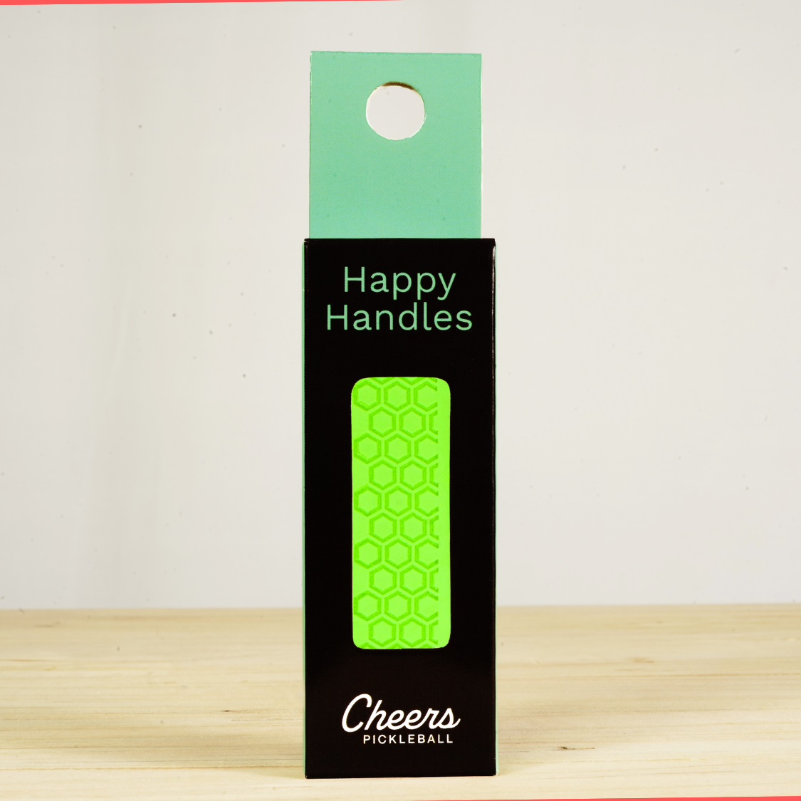 Happy Handles Pure Neon Green Pickleball Grip in its packaging, featuring hexagon textured print, visible through the product box window