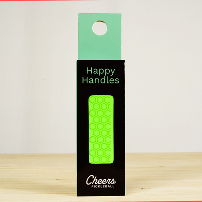 Happy Handles Pure Neon Green Pickleball Grip in its packaging, featuring hexagon textured print, visible through the product box window