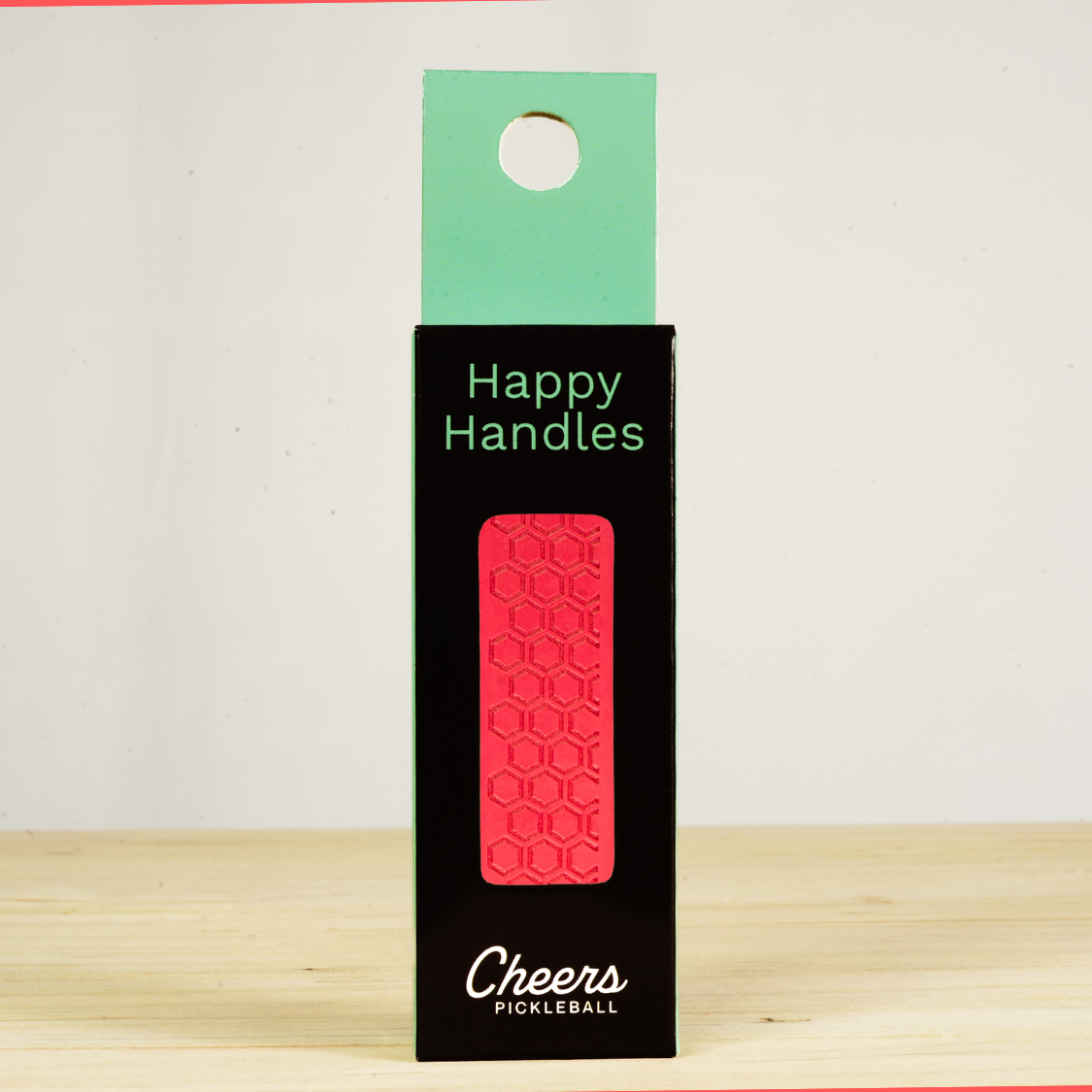 Happy Handles Pure Radiant Red Pickleball Grip in its packaging, featuring hexagon textured print, visible through the product box window